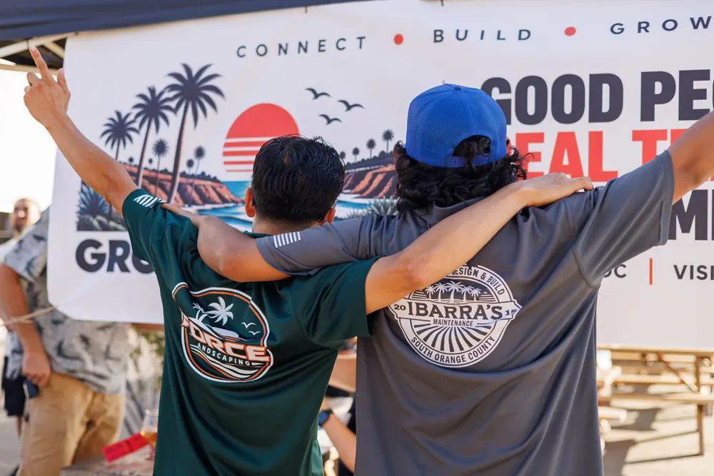 Two guys with their arms around each other in front of the Grow Love OC banner.
